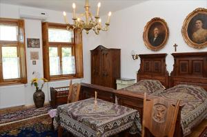 a bedroom with two beds and a table and a chandelier at Zengőalja Vendégház in Erzsébet
