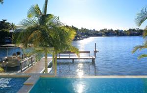 a pool with a bench and a dock on a lake at The Peninsula Secret - spacious waterfront & heated Spa in Noosaville