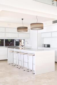 a white kitchen with white counters and stools at The Peninsula Secret - spacious waterfront & heated Spa in Noosaville