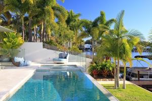 a swimming pool in a yard with palm trees at The Peninsula Secret - spacious waterfront & heated Spa in Noosaville
