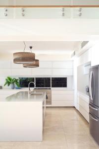 a white kitchen with a sink and a refrigerator at The Peninsula Secret - spacious waterfront & heated Spa in Noosaville +27 photos
