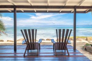 two chairs on a porch looking out at the ocean at Fare Matairoa - 2BR Beach Cottage in Iumaru