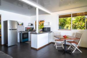 a kitchen with a table and a refrigerator at Fare Matairoa - 2BR Beach Cottage in Iumaru +16 photos