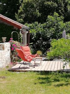 a red chair sitting on a wooden patio at Les séquoias in Javerdat