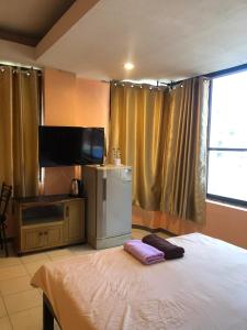 a bedroom with a bed and a flat screen tv at จอมเทียน ซีไซด์ เกสเฮ้าส์ in Jomtien Beach