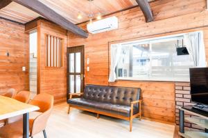 a leather bench in a room with a window at ウッドペッカーC棟BBQPetりんどう湖近くの一棟貸別荘 in Nasu