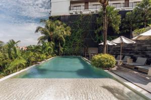 a swimming pool in front of a building at Astera Resort & Spa Canggu by Ini Vie Hospitality in Canggu