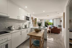 a kitchen with white cabinets and a living room at Classic Coastal Escape - 1 Bedroom Ocean Views in Maroochydore