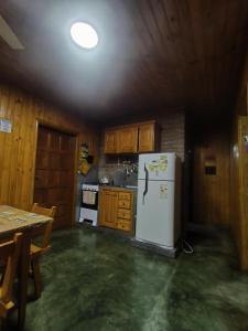 a kitchen with a white refrigerator and wooden cabinets at Silvia Cabaña Confort in Puerto Iguazú +5 photos