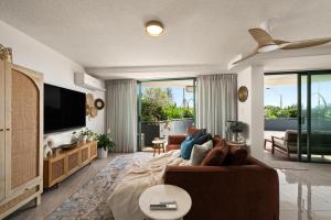 a living room with a couch and a flat screen tv at Classic Coastal Escape - 1 Bedroom Ocean Views in Maroochydore