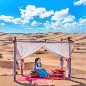 a woman sitting under a canopy in the desert at Best Classic Sahara Experiences in Merzouga +37 photos