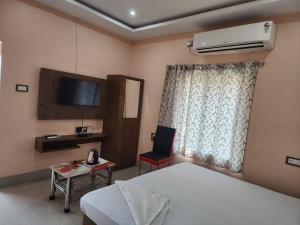 a bedroom with a bed and a desk and a television at Sheoak Retreat Tajpur in Tajpur