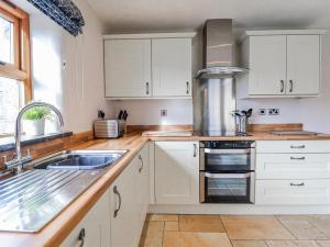 a kitchen with white cabinets and a sink at Briws in Llangwm