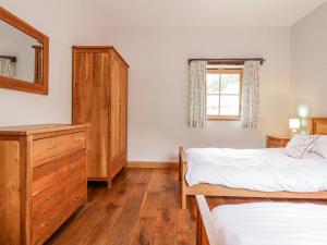 a bedroom with two beds and a dresser and a window at Briws in Llangwm
