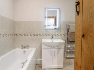 a bathroom with a sink and a bath tub and a mirror at Briws in Llangwm +24 photos