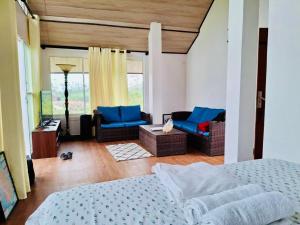 a bedroom with a bed and chairs and a living room at Moon Mist Villa in Kotagala