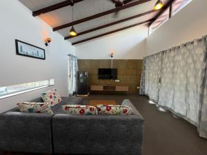 a living room with a couch and a television at Kimaya Cottage - 2BHK 1 Washroom in Trimbak