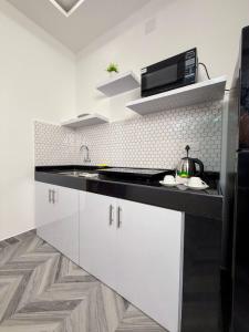 a white kitchen with a sink and a microwave at Bella Vista Extended Stay in Kalyānpur