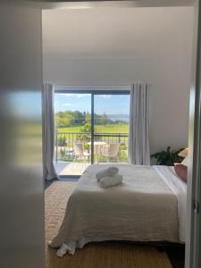 a bedroom with a bed with a view of a balcony at Corrigans Beach Escape Studio in Batehaven