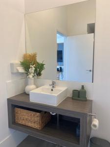 a bathroom with a white sink and a mirror at Corrigans Beach Escape Studio in Batehaven