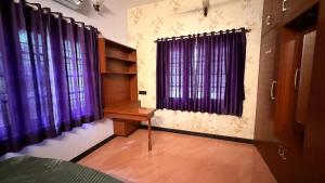 a bedroom with purple curtains and a desk in front of a window at Zeno Villa Malpe By Beach County in Udupi