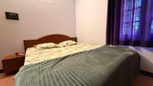 a bedroom with a bed and a window with purple curtains at Zeno Villa Malpe By Beach County in Udupi