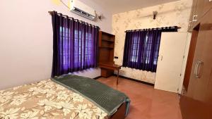 a room with a bed and two windows with purple curtains at Zeno Villa Malpe By Beach County in Udupi