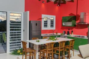 a kitchen with red walls and a table and chairs at Residence Can' Hibiscus in Le Marin