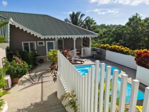a house with a white fence and a swimming pool at Residence Can' Hibiscus in Le Marin