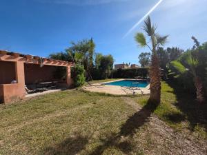 a backyard with a swimming pool and a palm tree at Ferme agafay in El Karia