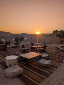 a sunset in the desert with a table and chairs at Ferme agafay in El Karia
