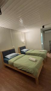 two beds in a room with green sheets at 5 Minutes Away Airport Lodge in Putatan +7 photos