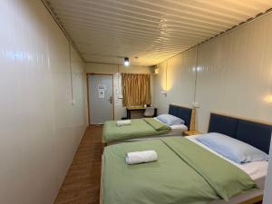 two beds in a room with green sheets at 5 Minutes Away Airport Lodge in Putatan