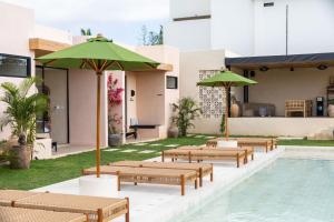 a group of benches with umbrellas next to a pool at Nema Uluwatu in Uluwatu