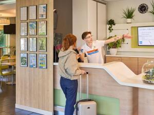 a man and a woman standing at a counter at ibis budget Wrocław Południe in Wrocław