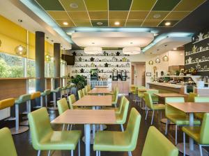 a restaurant with wooden tables and green chairs at ibis budget Wrocław Południe in Wrocław