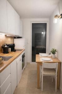 a kitchen with white cabinets and a wooden table at Le Paradis' c'est ici in Gréoux-les-Bains