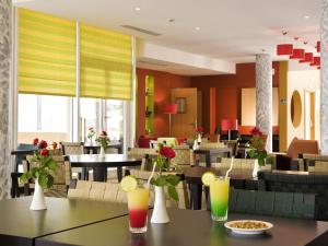 a restaurant with tables and chairs with drinks on them at Ibis Cotonou in Cotonou