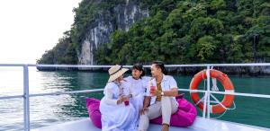 three people sitting on a boat in the water at Resorts World Langkawi in Pantai Cenang