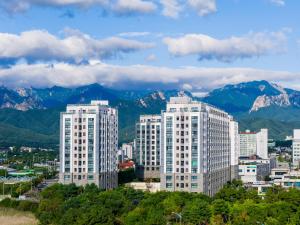 a city with tall buildings with mountains in the background at Chestertons Sokcho in Sokcho