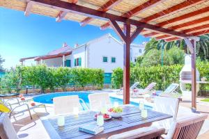 un patio con mesa, sillas y piscina en Villa Cvita 80 m from the sea, free breakfast - DIRECT LANDLORD, en Hvar