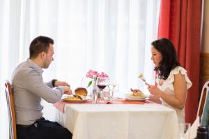 mężczyzna i kobieta siedzący przy stole jedzący jedzenie w obiekcie Platan Hotel w Debreczynie