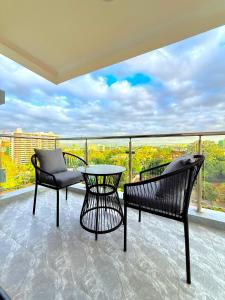 a balcony with a table and chairs and a view at Pearl Luxe Homes at Orchid Residency - Spacious 2BR in Westlands With Pool, Gym, Rooftop views & breakfast café in Nairobi