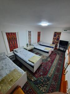 a room with two beds and a rug at Orzu Guest House in Bukhara +67 photos