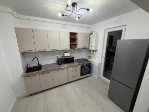 a kitchen with white cabinets and a refrigerator at White House in Ploieşti