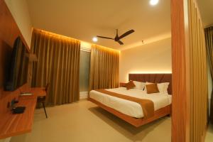 a bedroom with a bed and a desk and a television at Arunaragha in Mysore +41 photos