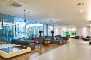a living room with couches and tables and windows at Chestertons Sokcho in Sokcho