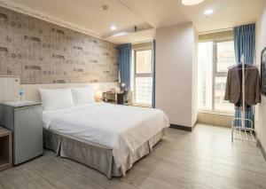 a bedroom with a large white bed and a window at Ezstay Station in Kaohsiung