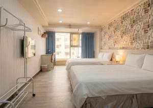 a hotel room with two beds and a television at Ezstay Station in Kaohsiung +43 photos