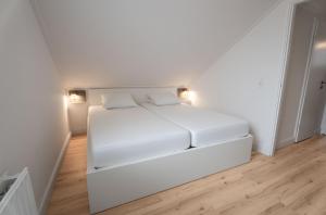 a white bed in a white room with wooden floors at Spaanse Galeien 13 in Retranchement